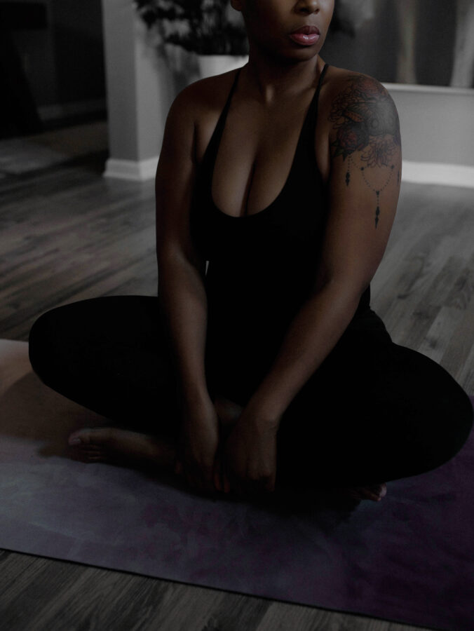 woman in moody photo sitting in cross legged yoga pose - sukhasana